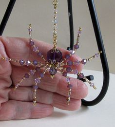 a hand holding a purple beaded snowflake ornament