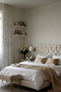 a white bed sitting next to a window in a room with curtains on the windowsill