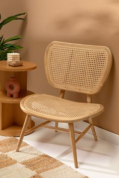 a wooden chair sitting next to a plant on top of a white carpeted floor