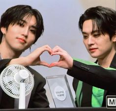 two young men making a heart with their hands while holding an award in front of them