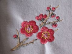 red flowers are embroidered onto white linen