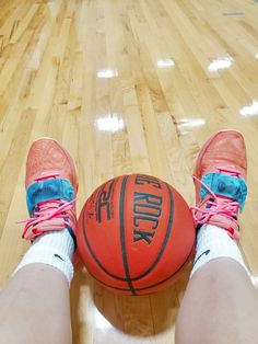 a person's feet with pink shoes on and a basketball in front of them