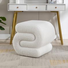 two white towels stacked on top of each other in front of a dresser and mirror