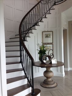 a spiral staircase in a home with potted plants on the table next to it