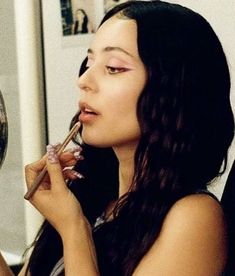 a woman with long black hair is holding a wine glass and looking at her reflection in the mirror