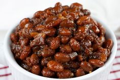 a white bowl filled with cooked beans on top of a red and white checkered table cloth