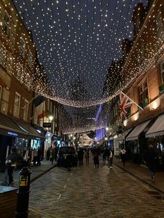 people are walking down the street under lights