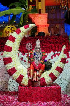 the statue is made up of flowers and has a man sitting on top of it