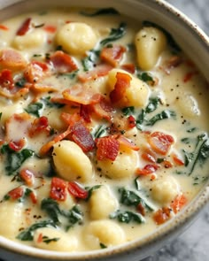 a white bowl filled with pasta and spinach on top of a marble countertop