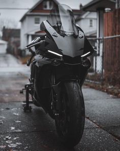 the motorcycle is parked on the side of the road in front of some houses and trees