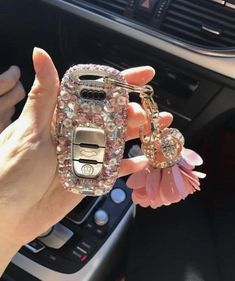 a person holding a cell phone in their hand with a flower on the keychain