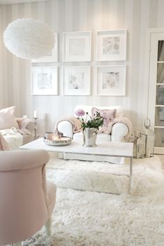 a living room filled with white furniture and pictures on the wall above it's coffee table