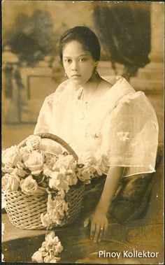 an old black and white photo of a woman holding a basket with flowers in it