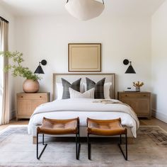 a bedroom with a bed, two chairs and a painting on the wall above it