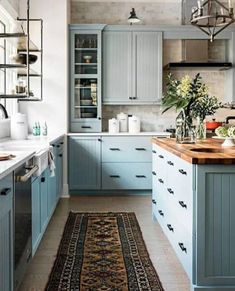 a kitchen filled with lots of blue cabinets and counter top space next to a rug