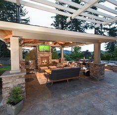 an outdoor living area with stone fireplaces and seating under a pergolated roof