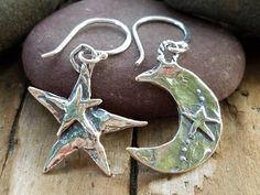 "These sterling silver, Artisan-crafted charms are on the large side with the star measuring 23mm x 24mm tall (not including the loop), and the moon measuring 21mm tall x 20mm at its widest area (height doesn't include loop). The star has the word, \"Reach\" inscribed on the back and a double star on the front. The moon has a raised star and dots on the front. The charms are hung from sterling silver fishhook ear wire. The earrings have a total length of 38mm (approximately 1-1/2\") from the top Whimsical Star-shaped Jewelry With Star Charm, Celestial Silver Earrings With Star Charm, Silver Crescent Earrings With Star Charm, Silver Star Earrings With Charms, Symbolic Star Shaped Earrings For Gift, Symbolic Silver Moon Charm Earrings, Silver Moon Charm Earrings, Symbolic Silver Earrings With Moon Charm, Silver Symbolic Moon Charm Earrings