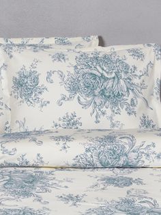 a bed with blue and white floral print on the sheets, pillows and pillow cases