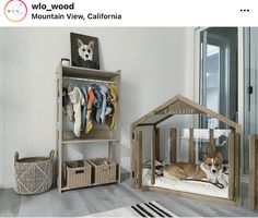 a dog laying in his bed next to a wooden house with clothes hanging on it