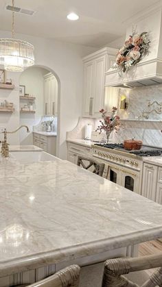 a large kitchen with white cabinets and marble counter tops, along with an island in the middle