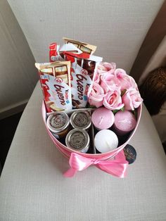 a pink flower arrangement with candy, candies and roses in a bowl on a chair