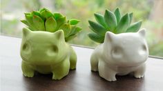 two ceramic animals sitting next to each other on a window sill with succulents