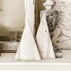 two white vases sitting next to each other on top of a shelf in front of a mirror