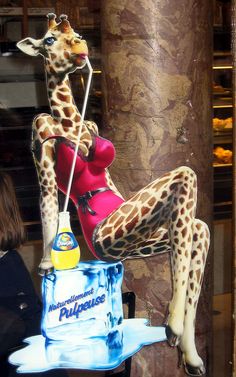 a fake giraffe sitting on top of a table next to a blue bottle