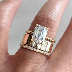 a woman's hand with two gold rings and an engagement ring on top of her finger