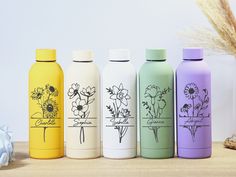 four different colored bottles with flowers on them