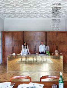 a man and woman sitting at a table in front of a large mirror on the wall