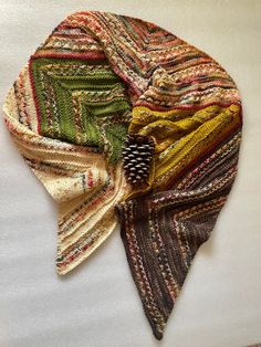 a multicolored scarf with a pine cone on it's end laying on a white surface