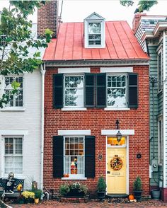 a red brick house with black shutters and a yellow door