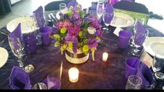 the table is set with purple napkins and place settings