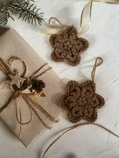 two brown crocheted ornaments tied to twine on top of a white table