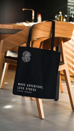 a black tote bag sitting on top of a wooden chair next to a table