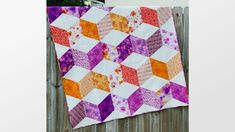 a colorful quilt hanging on the side of a wooden fence