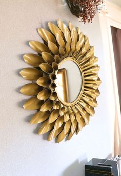 a gold sunflower shaped mirror hanging on the wall next to a black and white clock