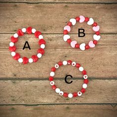 two red, white and black beads are arranged in the shape of letters on a wooden surface