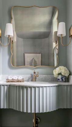 a white sink sitting under a mirror in a bathroom next to a wall mounted faucet