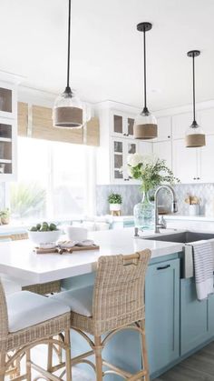 a kitchen with blue cabinets and wicker chairs in front of an island countertop