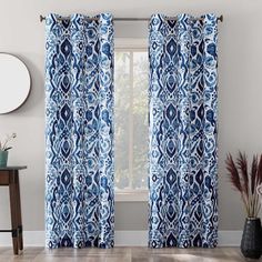 a blue and white curtain hanging in front of a window next to a potted plant