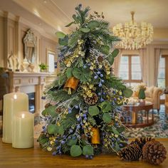 a decorated christmas tree sitting on top of a wooden table next to a lit candle