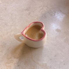 a heart shaped coffee cup sitting on top of a table