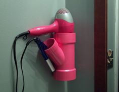 a pink hair dryer sitting on top of a wall