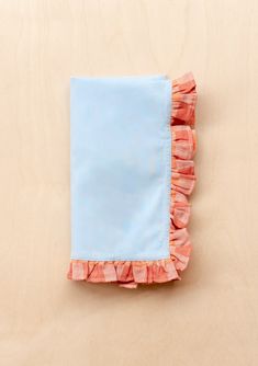 a blue and pink napkin with ruffles on it sitting on top of a wooden table