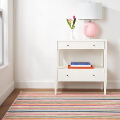 a white table with a pink lamp and some books on it