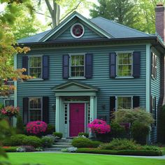 a blue house with pink flowers in the front yard