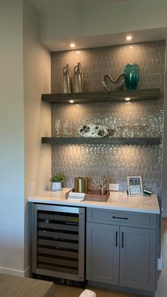 a kitchen area with shelves, cabinets and wine glasses on the top shelf in front of it