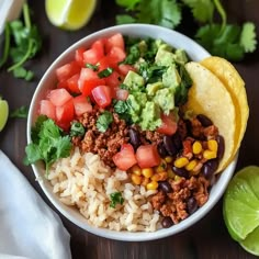 a white bowl filled with rice, black beans and guacamole next to limes